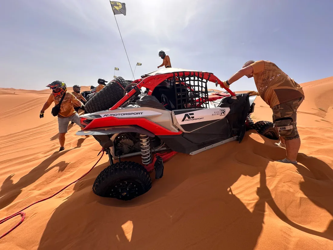 Ekipa wypychająca zakopany Can-Am Maverick X3 na wydmach Sahary podczas rajdu SSV w Maroku